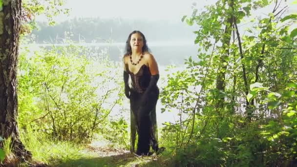 Une femme est une sorcière vêtue de noir sur la rive d'un lac. Halloween. Style gothick . — Video