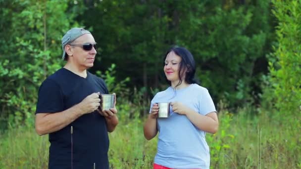 Un homme et une femme au bord de la forêt boivent du thé . — Video