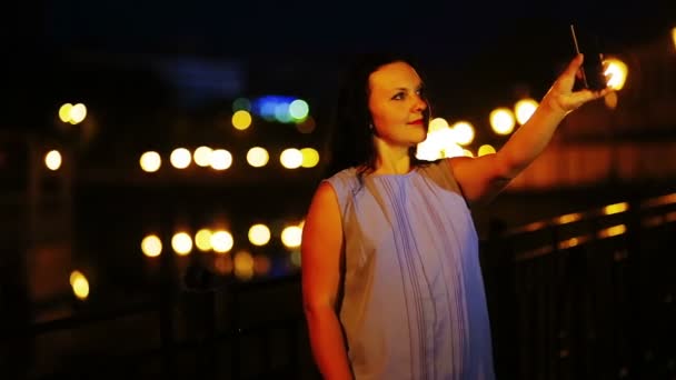 一个年轻的女孩正在用手机自拍夜空的背景。. — 图库视频影像