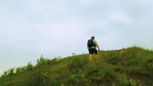 Jako turista s batohem na zádech šplhá do kopce. Čas kola. — Stock video