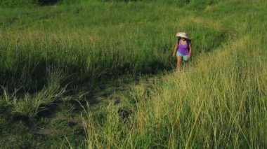 Hasır şapkalı bir kadın bir dağ yolunda tırmanıyor. En baştan çekim.