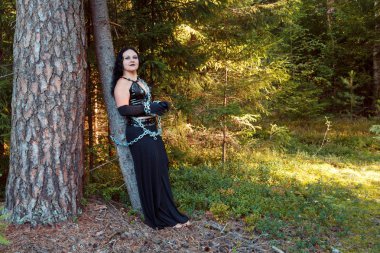 Ormandaki bir ağaç zincirli siyah genç kadın cadı. Cadılar Bayramı.