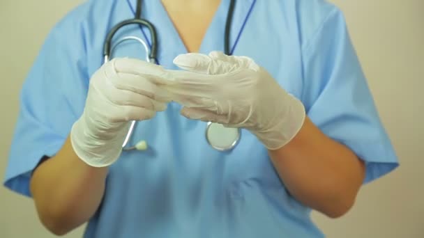 Женщина-врач снимает медицинские перчатки . — стоковое видео