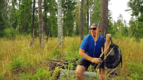 Un turista masculino en un bosque se pone una mochila y emprende un viaje . — Vídeos de Stock