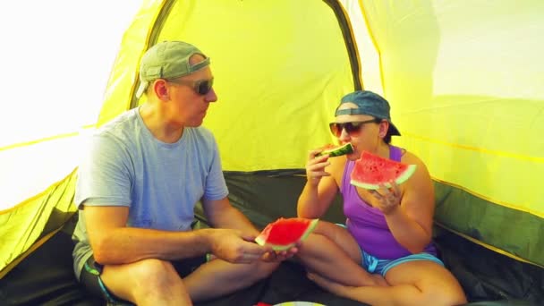 Mann und Frau im Zelt essen eine Wassermelone. — Stockvideo