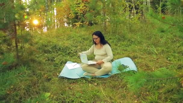 Mulher jovem em uma clareira florestal com um laptop — Vídeo de Stock