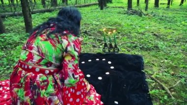 Çingene shuvany ormandaki üzerinde yanan mumlar ve beyaz çakıl elle sihirli hareketler yapar. Genel planı.