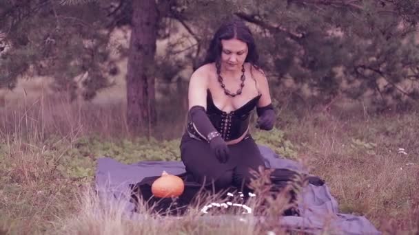 A young witch in black performs magical movements with his hands over white stones. Halloween. — Stock Video