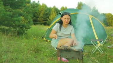 Bir erkek ve bir kadın tarafından çadır oturan ve ızgara et ızgara.