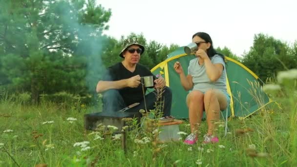 Un hombre y una mujer turistas comen carne frita y beben té . — Vídeo de stock