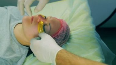 bir erkek güzellik uzmanı eldiven eller kollajen yastıkları kadının yüzünde gözlerinin altında empoze. Yakın çekim.