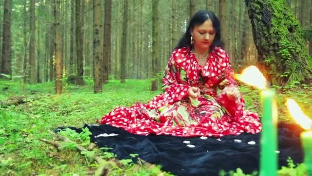 En ung zigenare kvinna lampor ljus i en cirkel i skogen. — Stockvideo