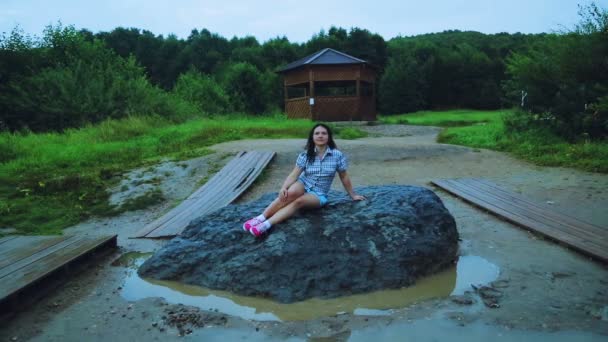 Ένας ταξιδιώτης νεαρή γυναίκα κάθεται σε έναν τεράστιο βράχο, εκπληρώνοντας τις επιθυμίες. — Αρχείο Βίντεο