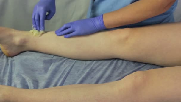 一个美容师的手在女孩的腿皮肤上涂抹糖糊 — 图库视频影像