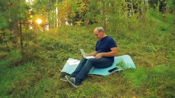 Ein Mann Mit Brille Auf Einer Waldlichtung Tippt Auf Einer — Stockvideo