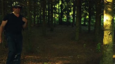 bir adam bir sırt çantası ile ormanın içinden elini kolunu sallaya dönüyor. yakın çekim.