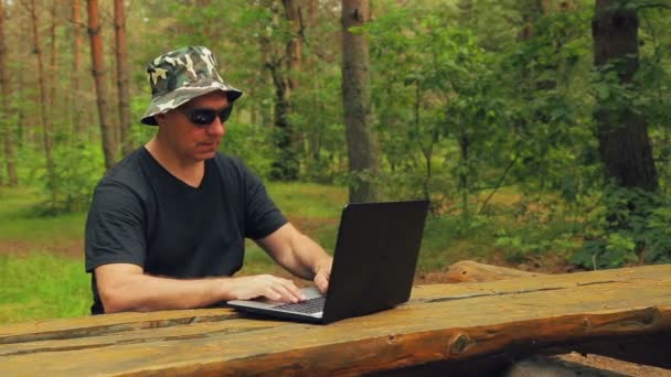 男子在公园的长椅上的太阳镜工作与笔记本电脑 — 图库视频影像