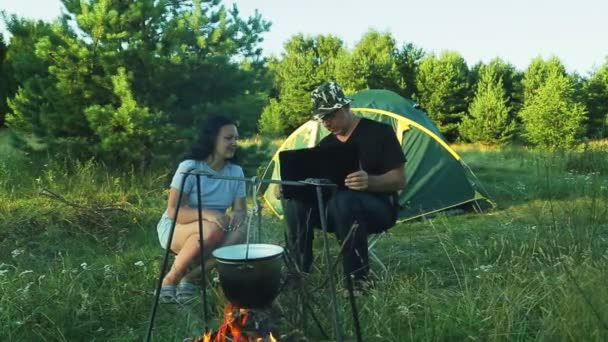 Мужчина Женщина Туристы Сидят Палатке Наблюдая Горшок Висит Над Огнем — стоковое видео
