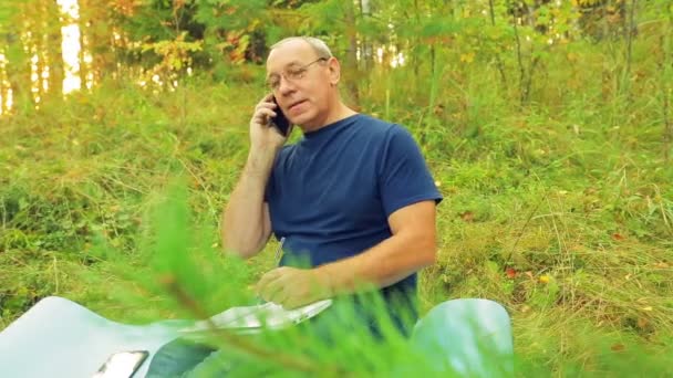 Ένας Άνδρας Στο Δάσος Λειτουργεί Ένα Σημειωματάριο Και Μιλά Στο — Αρχείο Βίντεο