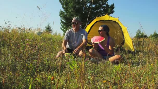 一个男人和一个女人在森林里的旅游帐篷旁切吃西瓜 — 图库视频影像