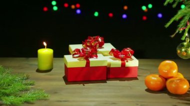 Güzel bir Noel ağacı ve yanan bir mum ışıkları siyah bir zemin üzerine yanında hediye kutularıyla.