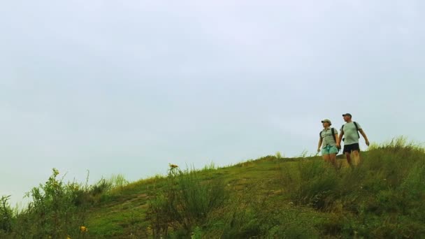 Man and woman travelers descend from the mountain. — Stock Video