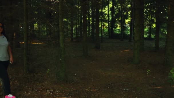 Une femme avec un sac à dos se promène dans la forêt par une journée ensoleillée — Video