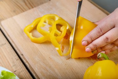 Sarı biber bıçakla küçük parçalara bir bıçakla bir kesme tahtası eller close-up üzerinde