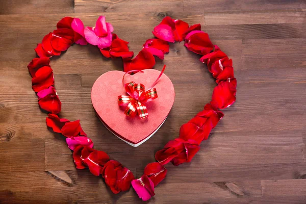 Ahşap masanın üstüne gül lepistas kalp içinde bir hediye bir kalp şeklinde bir kutudur. Kopya alanı