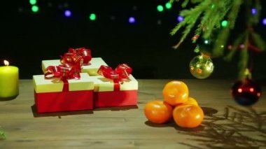 Güzel bir Noel ağacı ve siyah bir arka plan ile ışık ahşap bir masa üzerinde yanan bir muma yanında hediye kutularıyla.