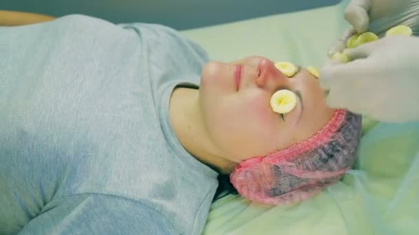 Tours de temps. mains d'un cosmétologue masculin en gants imposent aux femmes des morceaux de visage d'une banane — Video