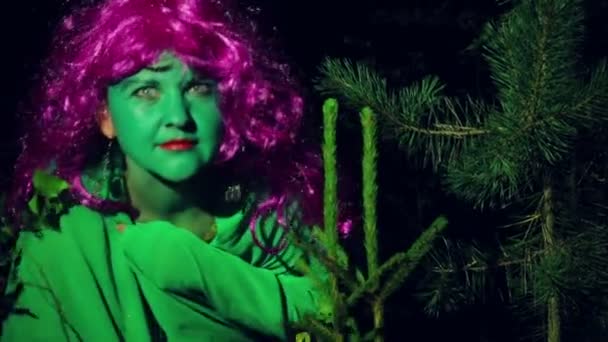 A green witch peeps out of the forest undergrowth at night. — Stock Video