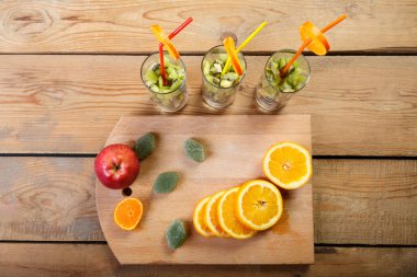 bir kesme tahtası üzerinde ahşap bir masa üzerinde portakal, elma ve marmelat meyve parçaları olan gözlük yanındaki parçaları nelerdir