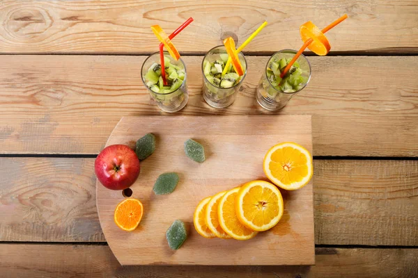 bir kesme tahtası üzerinde ahşap bir masa üzerinde portakal, elma ve marmelat meyve parçaları olan gözlük yanındaki parçaları nelerdir