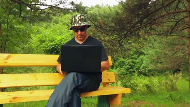 De man in het park is werken met een laptop. — Stockvideo