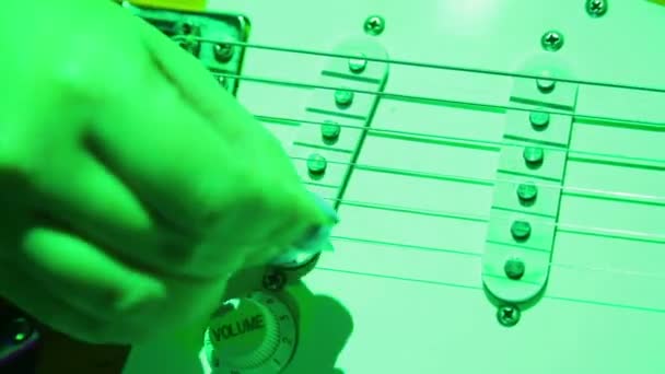 Female hand picks guitar strings with a pick. Concert lighting. — Stock Video