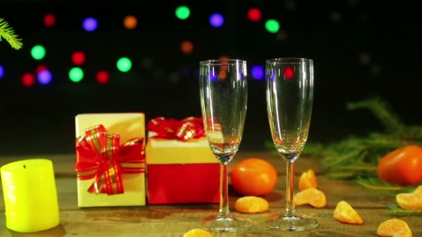 여성 손 크리스마스 선물과 샴페인 안경 옆 테이블에 촛불을 조명 — 비디오