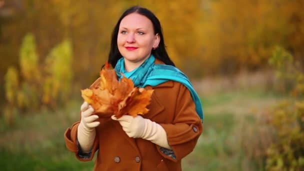 Μια νεαρή γυναίκα το φθινόπωρο στο πάρκο θαυμάζει ένα μπουκέτο από φύλλα σφενδάμου στα χέρια της. Αργή κίνηση. — Αρχείο Βίντεο