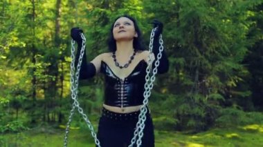 Siyah giysili genç cadı serbest zincirleri, ormanın içinde onlarla danslar dan. Cadılar Bayramı. Gothick tarzı