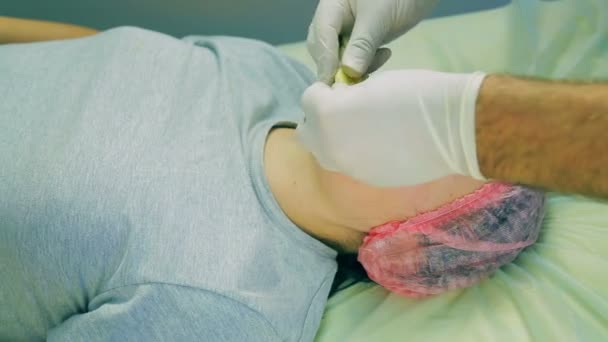 Händerna på en manlig kosmetolog i handskar ålägga kvinnans ansikte bitar av en banan — Stockvideo
