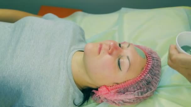 Czas okrążeń. Ręce człowieka kosmetyczka umieścić na twarzy kobiety płyn zielony maskę za pomocą pędzla. — Wideo stockowe
