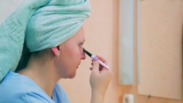 Una giovane donna applica una maschera di fango sul viso con un pennello. Primo piano . — Video Stock