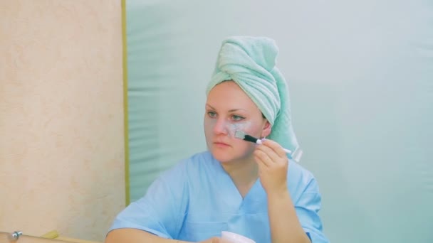 L'actrice de la ville se regarde dans le miroir et met un masque sur son visage avec une brosse . — Video