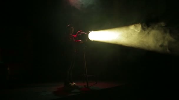 Uma mulher iluminadora dirige um feixe de luz de um holofote de perfil — Vídeo de Stock