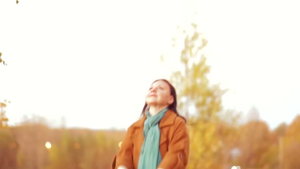 Una mujer joven en el parque lanza hojas de arce en el aire en el otoño. Movimiento lento . — Vídeo de stock