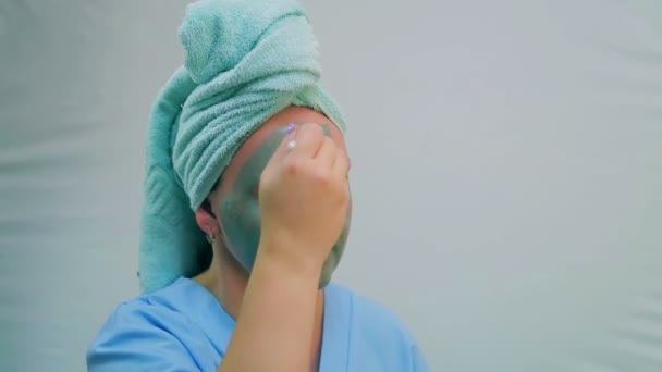 Una joven en el baño se está poniendo una máscara de barro en la cara con un cepillo. Primer plano . — Vídeo de stock
