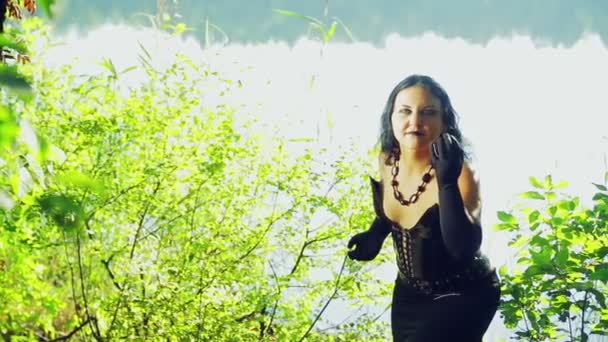 Naštvaná čarodějka v černých šatech na břehu jezera. Halloween. Zvláště styl. — Stock video