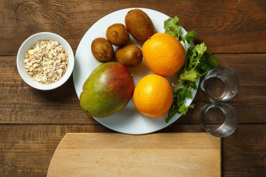 Beyaz tabak portakal, mango, kivi yalan ahşap bir masaya. Yatay resim. üstten görünüm