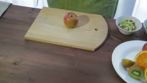 一个女人用刀子把苹果切成两块 相机从左到右移动 — 图库视频影像