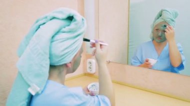 Bir fırça ile yüzünde bir maske bir ayna önünde bir makyaj odasında genç bir oyuncu koyar.